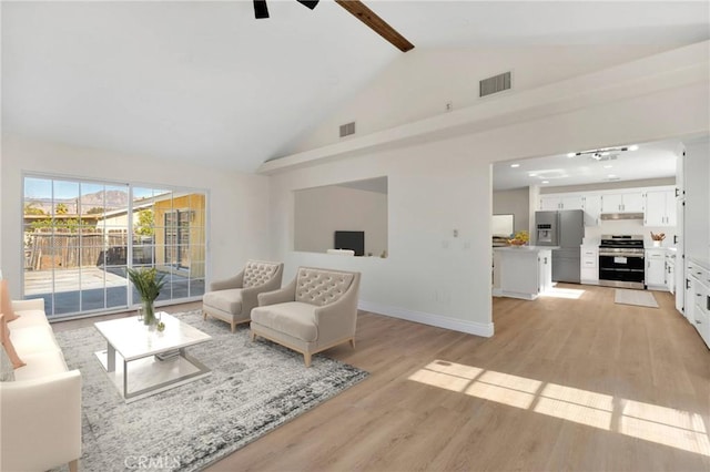 living room with light wood-type flooring and vaulted ceiling with beams