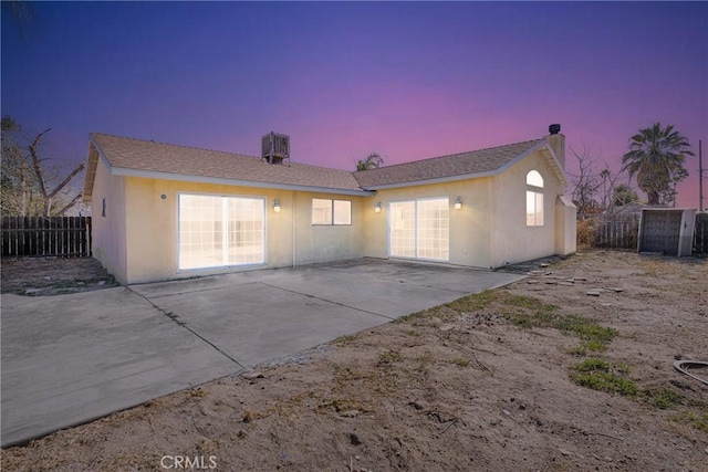 back house at dusk featuring central AC unit and a patio area