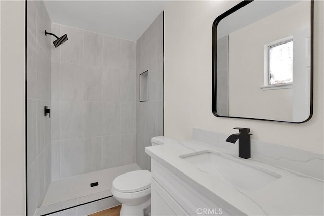 bathroom featuring vanity, toilet, and tiled shower