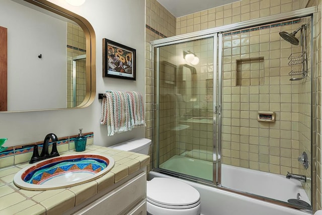 full bathroom featuring vanity, enclosed tub / shower combo, and toilet