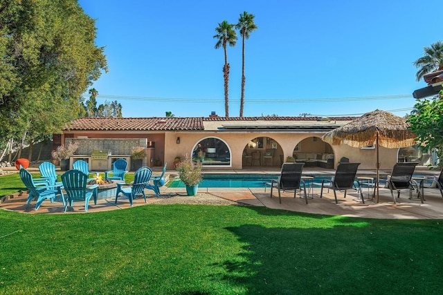 back of house with a fire pit, a yard, and a patio