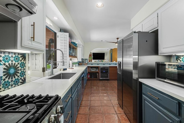 kitchen featuring ventilation hood, sink, white cabinets, wine cooler, and blue cabinetry