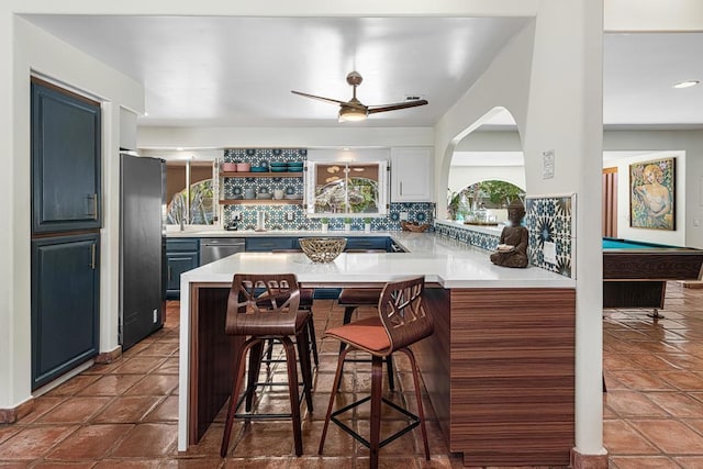 kitchen featuring a breakfast bar, refrigerator, kitchen peninsula, dishwasher, and backsplash