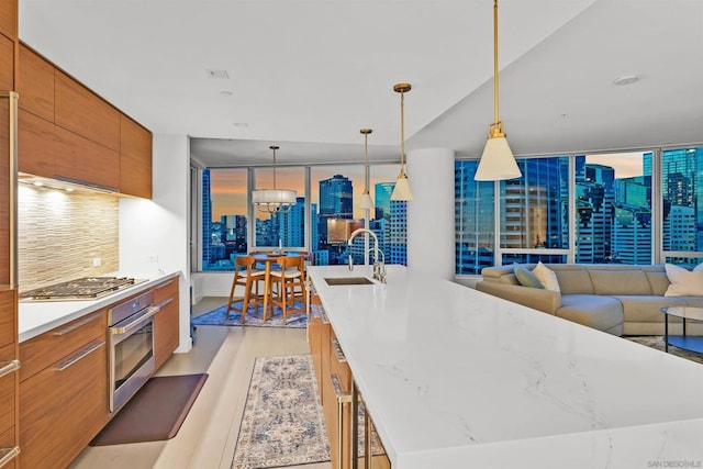 kitchen featuring pendant lighting, sink, appliances with stainless steel finishes, tasteful backsplash, and a large island with sink