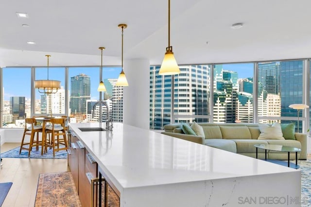 kitchen featuring sink, pendant lighting, a kitchen island with sink, and light hardwood / wood-style floors