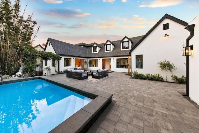 pool at dusk featuring a patio and outdoor lounge area