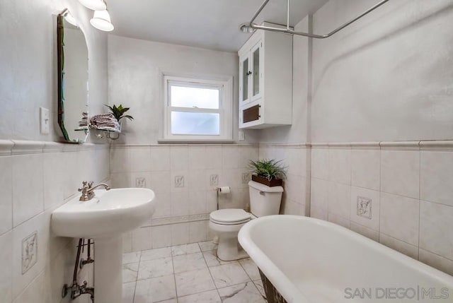 bathroom with a tub, tile walls, and toilet