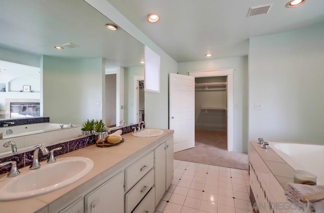 bathroom with tile patterned floors, a tub to relax in, and vanity