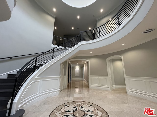 stairs featuring a towering ceiling and crown molding