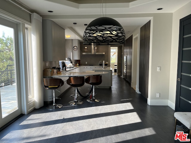 kitchen with pendant lighting, a breakfast bar, a wealth of natural light, and kitchen peninsula