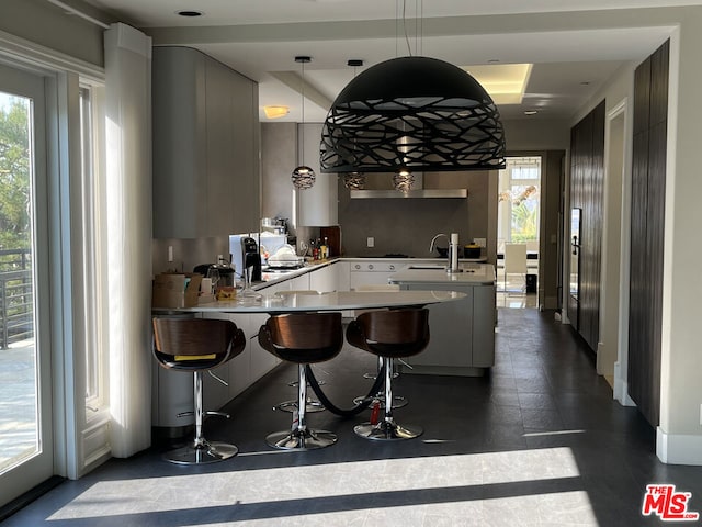 kitchen with a wealth of natural light, hanging light fixtures, kitchen peninsula, and a kitchen breakfast bar