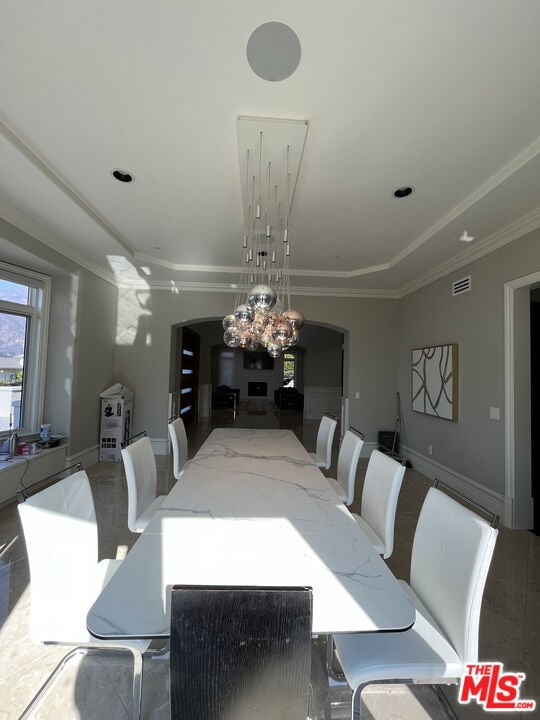 dining space with a raised ceiling and a notable chandelier