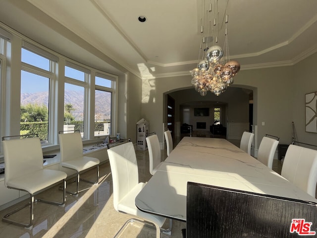 dining room with a mountain view, a raised ceiling, an inviting chandelier, and crown molding