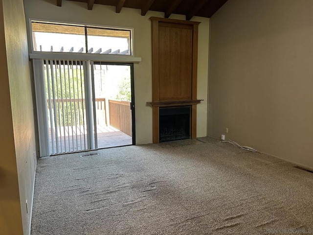 unfurnished living room with carpet flooring, beam ceiling, and a fireplace