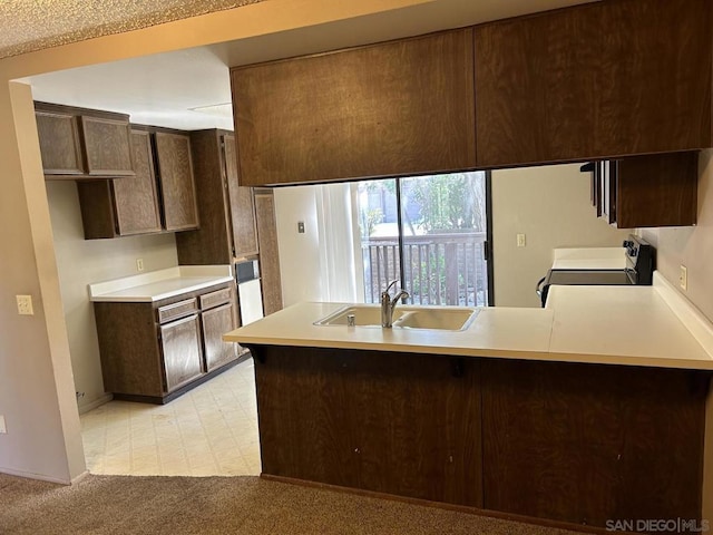 kitchen featuring sink, kitchen peninsula, stove, and dark brown cabinets