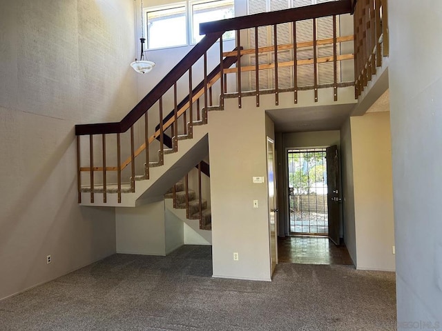 stairs with a wealth of natural light, a towering ceiling, and carpet flooring