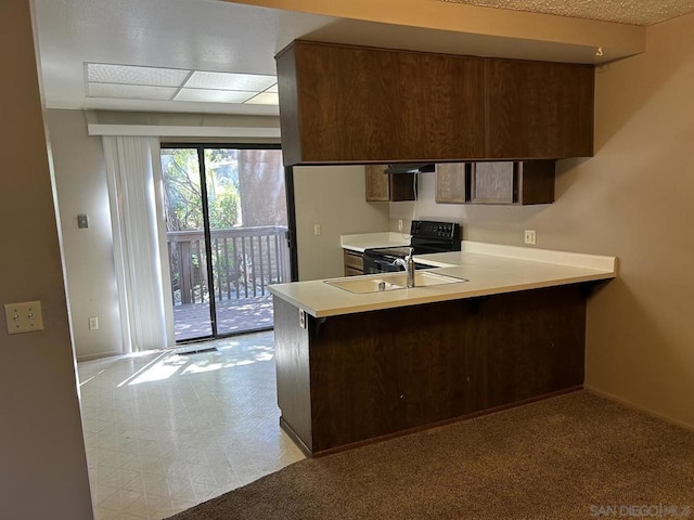 kitchen with dark brown cabinets, black range with electric stovetop, kitchen peninsula, and sink