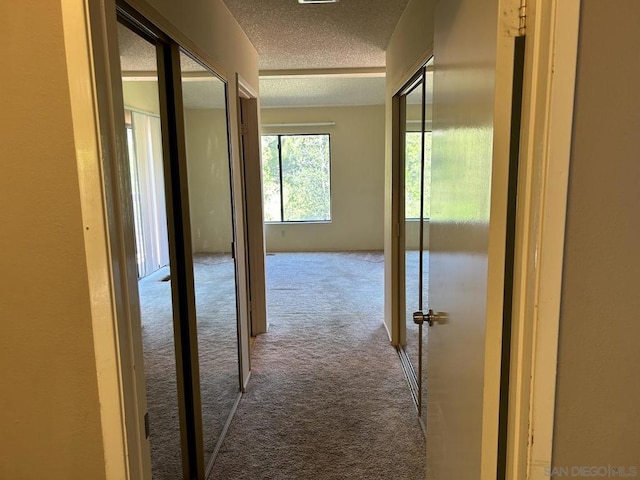 hall with a textured ceiling and carpet floors