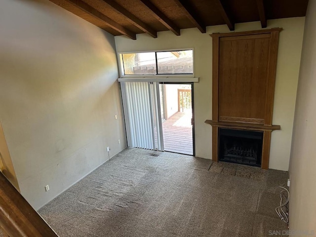 unfurnished living room featuring a fireplace, beamed ceiling, and carpet