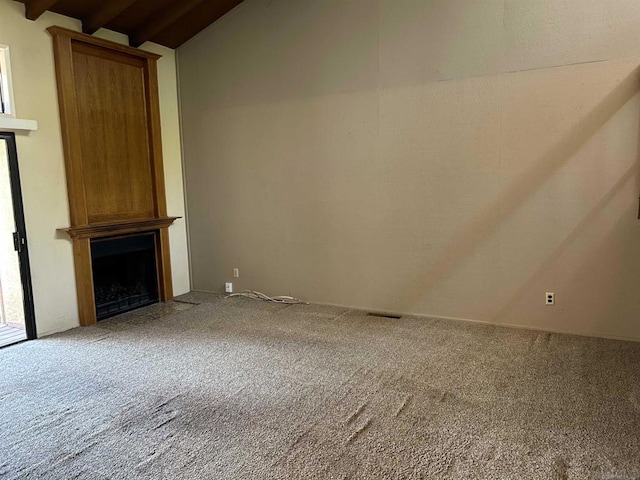 unfurnished living room with a large fireplace, carpet floors, and lofted ceiling with beams