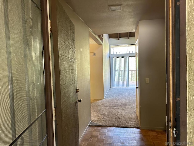 corridor with parquet flooring, a textured ceiling, and beam ceiling