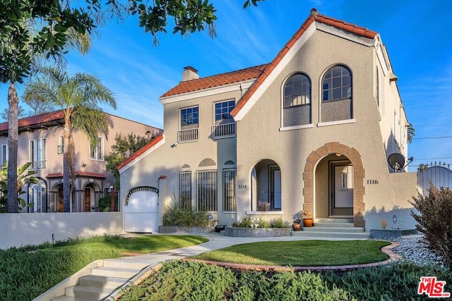 mediterranean / spanish-style house featuring a garage and a front lawn