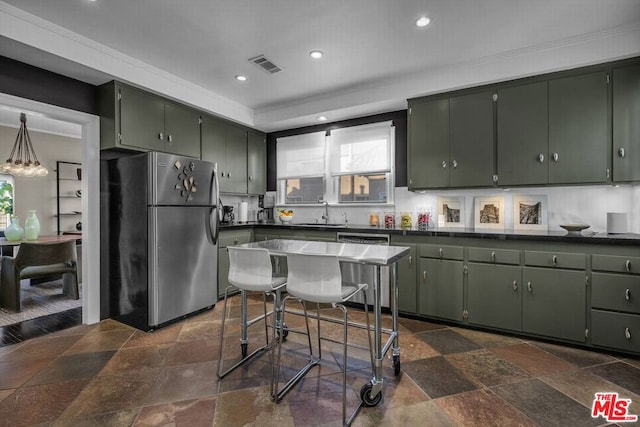 kitchen featuring crown molding, stainless steel refrigerator, green cabinetry, sink, and backsplash