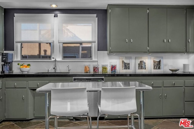 kitchen featuring sink, tasteful backsplash, green cabinets, and dishwasher