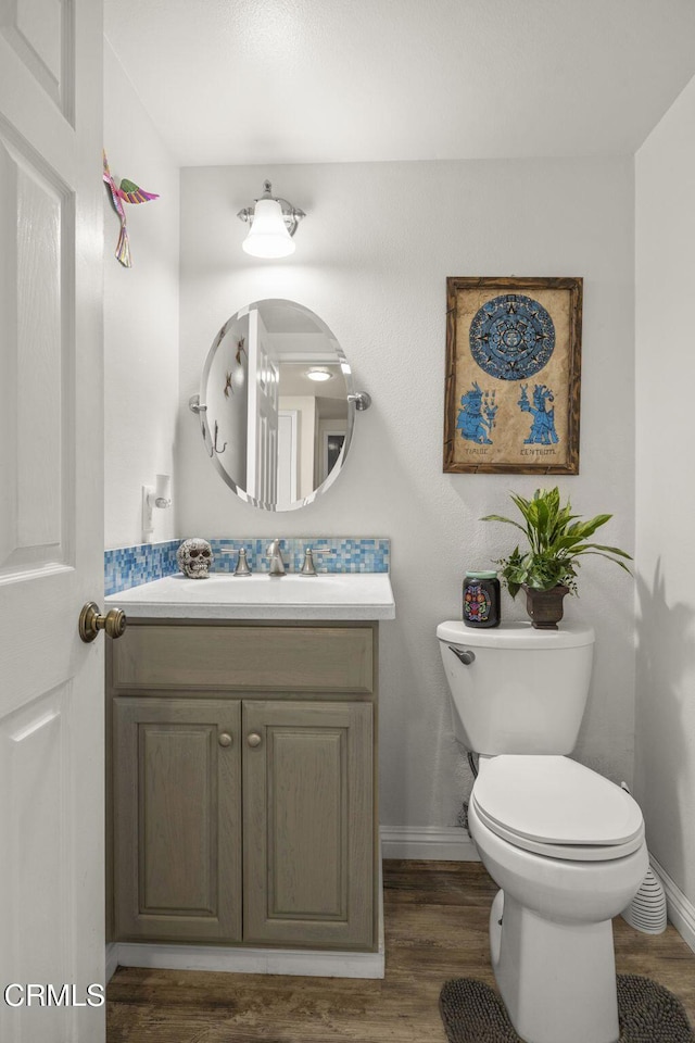 bathroom with wood-type flooring, toilet, and vanity