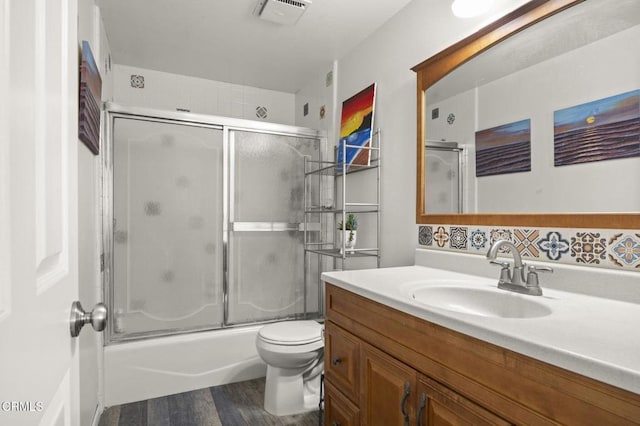 full bathroom featuring vanity, toilet, combined bath / shower with glass door, and hardwood / wood-style floors