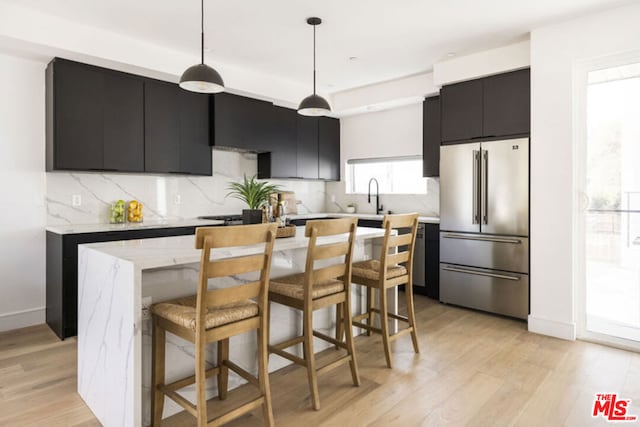 kitchen featuring a kitchen island, a kitchen breakfast bar, high end fridge, and hanging light fixtures