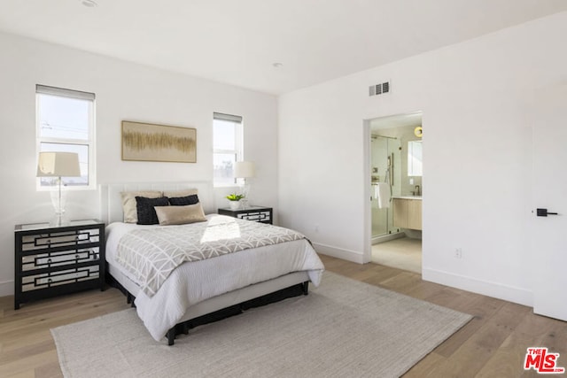 bedroom with ensuite bathroom and light wood-type flooring