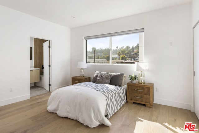 bedroom with light wood-type flooring and ensuite bath