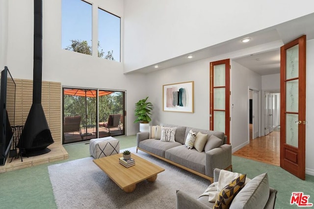 carpeted living room with a towering ceiling and a wood stove