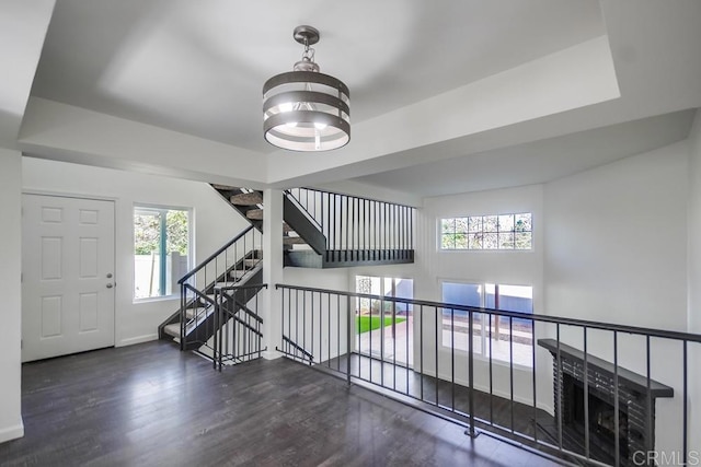 interior space with a notable chandelier, a tray ceiling, and dark hardwood / wood-style flooring