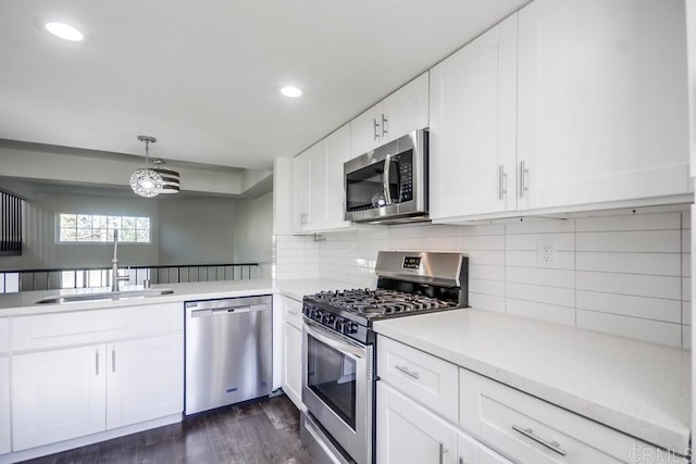 kitchen featuring appliances with stainless steel finishes, hanging light fixtures, decorative backsplash, white cabinets, and sink