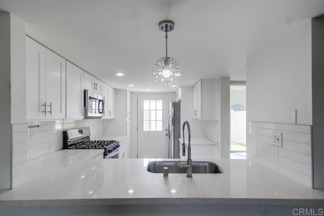 kitchen featuring sink, white cabinetry, light stone counters, and appliances with stainless steel finishes