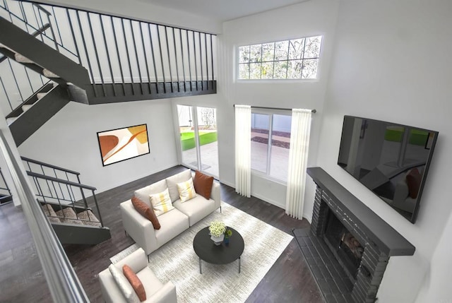 living room featuring a towering ceiling, dark wood-type flooring, and a fireplace