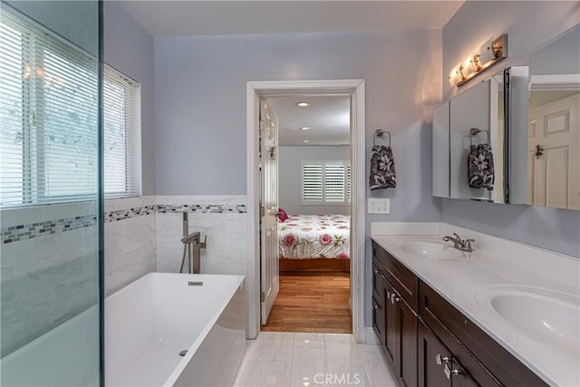 bathroom featuring a tub, a healthy amount of sunlight, tile walls, and vanity