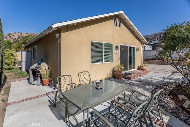 back of property with a mountain view and a patio