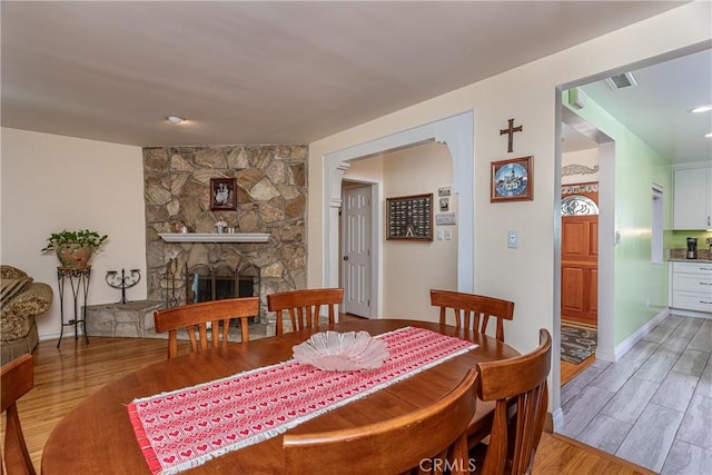 dining space featuring light hardwood / wood-style floors and a stone fireplace