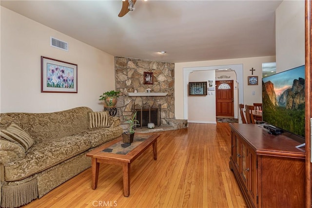 living room with ceiling fan, light hardwood / wood-style flooring, and a fireplace