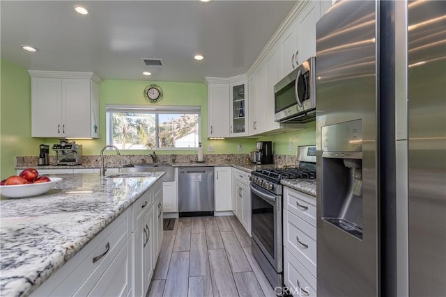 kitchen featuring light stone counters, sink, white cabinets, and stainless steel appliances