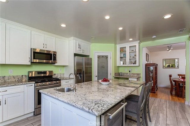 kitchen featuring sink, an island with sink, white cabinets, and appliances with stainless steel finishes