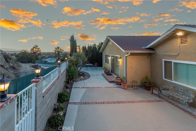 property exterior at dusk featuring a patio