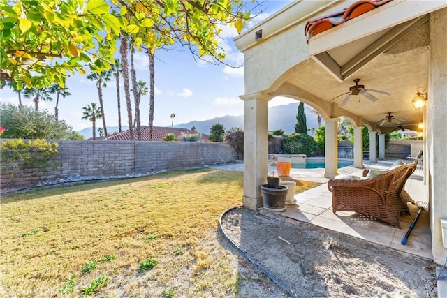 view of yard featuring a mountain view, a fenced in pool, ceiling fan, and a patio