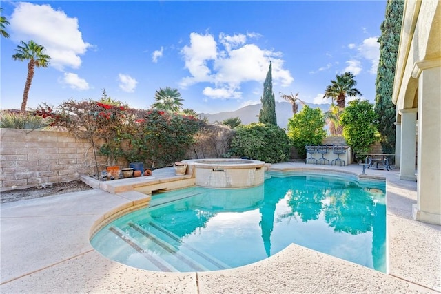 view of swimming pool with an in ground hot tub, an outdoor bar, a mountain view, and a patio