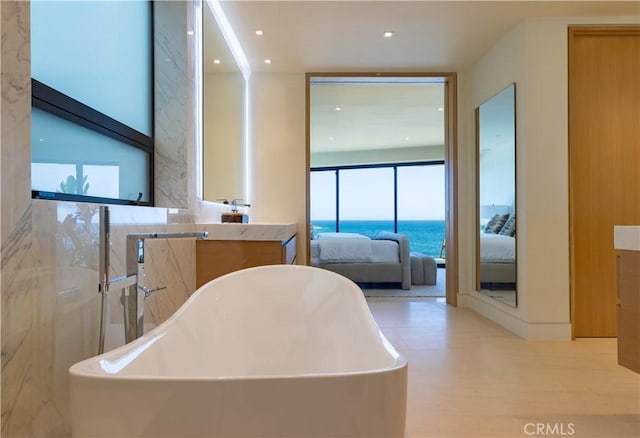 bathroom with hardwood / wood-style flooring, a washtub, vanity, and a water view