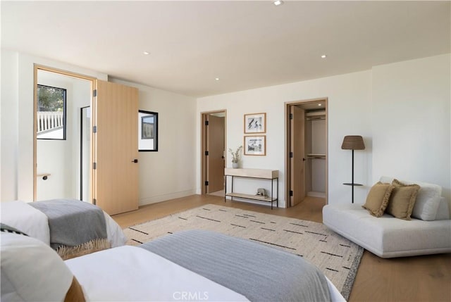 bedroom with a spacious closet, light hardwood / wood-style flooring, and a closet