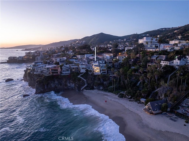 aerial view at dusk with a view of the beach and a water and mountain view